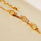A gold chain bracelet with three oval bezel-set clear stones, photographed close-up on a warm cream surface.