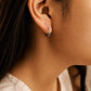 Woman wearing pavé-set hoop, often featuring clear cubic zirconia stones in a 925 silver setting. These are classic, versatile pieces known for their subtle sparkle, perfect everyday earrings.