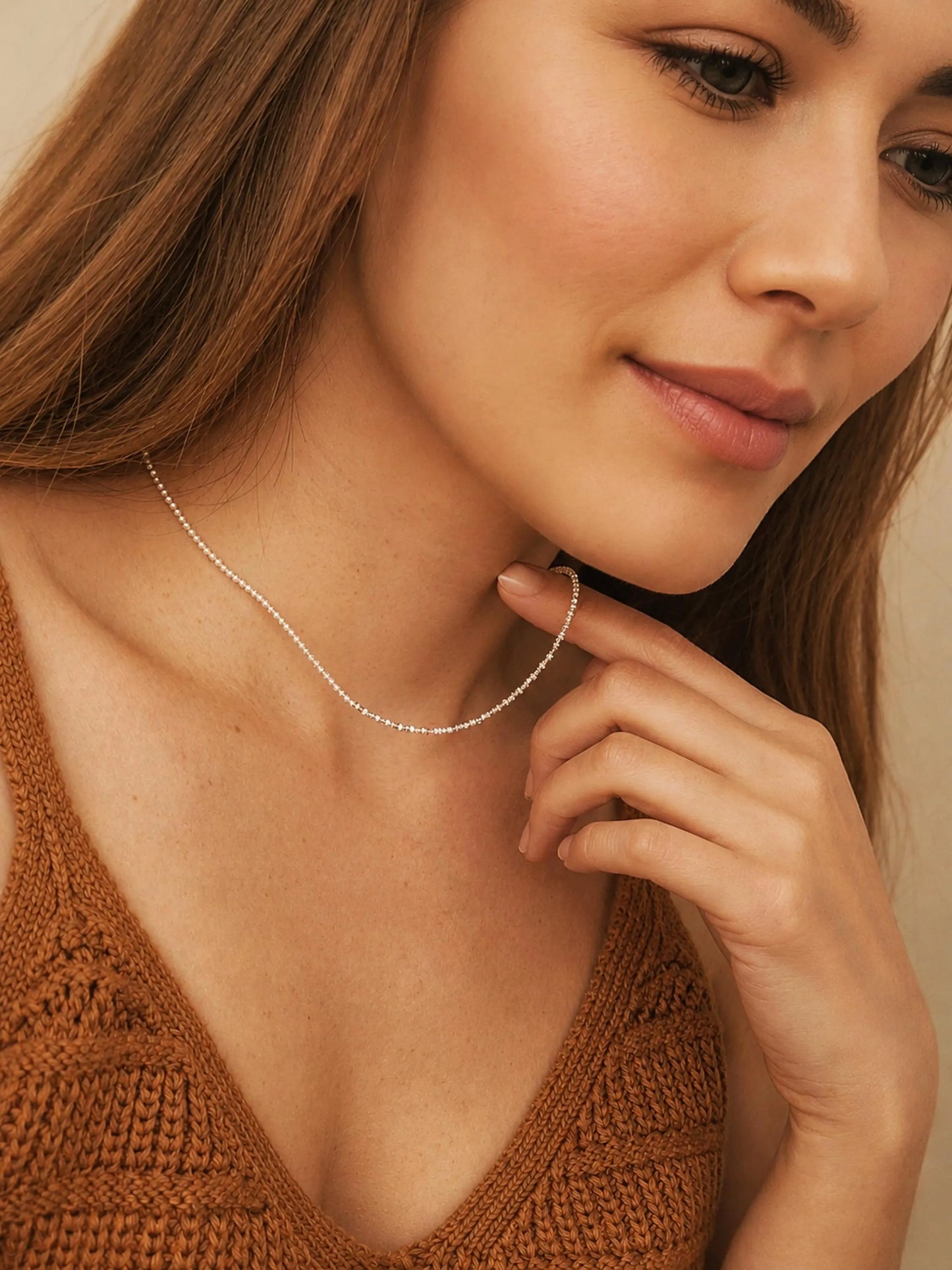 Close-up of a woman wearing a delicate, minimalist choker necklace made of tiny white glass pearls and a textured row of shimmering sterling silver nuggets.