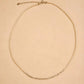 A dainty 2mm glass pearl choker necklaces displayed on a luxury beige color surface featuring textured sterling silver nugget beads.