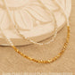 Two dainty 2mm glass pearl choker necklaces displayed on a decorative stone tile, one featuring textured 18k gold-plated nuggets and the other with sterling silver nuggets.