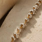 Close up of a mixed metal bracelet featuring two tone with gold and silver on a textured beige surface
