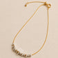 A mixed metal bracelet with delicate organic shaped sterling silver beads on a fine gold chain with measurement label on a beige background