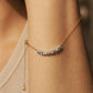 Organic sterling silver beads on a gold chain worn on a wrist against a neutral background
