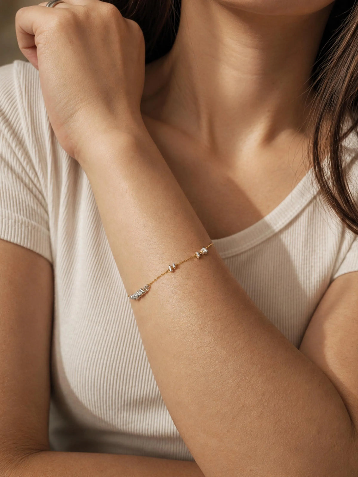 Close-up of a person wearing a delicate mixed metal bracelet with movable beads.