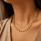 Close-up model photo showcasing a delicate, dainty beaded necklace made of warm brown tiger's eye and light yellow citrine beads. The necklace sits gracefully on the collarbone, styled against a soft beige v-neck top.
