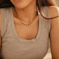 Close-up model photo showcasing a delicate, dainty beaded necklace made of warm brown tiger's eye and light yellow citrine beads. The necklace sits gracefully on the collarbone, styled against a soft beige tank top.