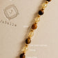 Close-up of a delicate gemstone necklace featuring alternating smooth round tiger's eye beads, faceted translucent yellow citrine beads, and small 22k gold vermeil spacers. Annotations show 3mm bead sizing set against a warm beige textured background with an embossed JaBelle Jewellery logo.