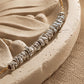 Detailed view of sculptural sterling silver nugget beads arranged along a gold chain on a curved beige stone surface.