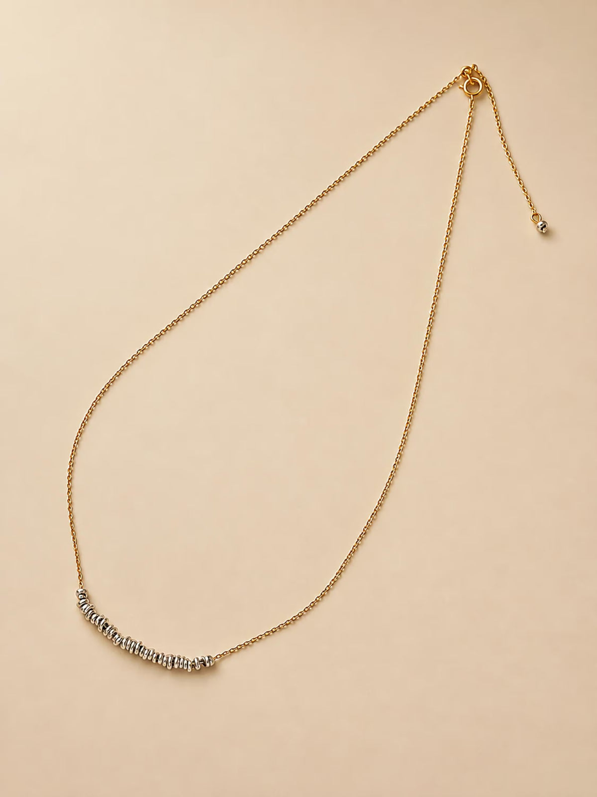 Full adjustable mixed-metal necklace displayed on a cream background, featuring a fine gold chain and movable silver beads.