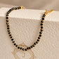 A dainty black onyx beaded bracelet with gold vermeil accents, displayed on a textured JaBelle Jewellery box.