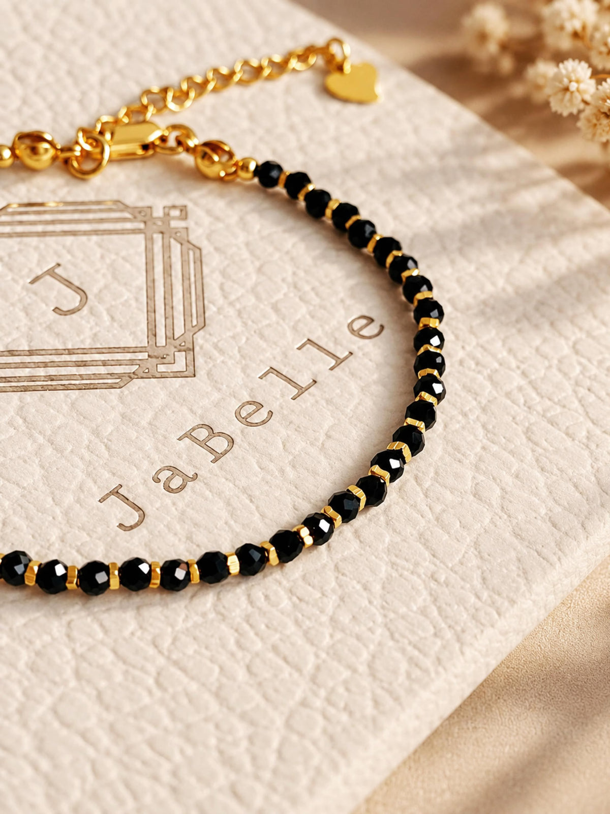 Black onyx beaded bracelet with tiny faceted black gemstones and delicate gold details displayed on a neutral jewellery card.