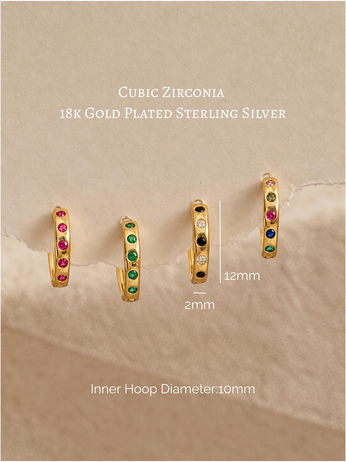 Four gold-plated huggie hoop earrings with cubic zirconia stones in pink, green, black, and multicolor settings, displayed on a textured beige background with text detailing the materials and dimensions.