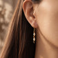 Side profile view of a model wearing delicate Tiger's Eye gemstone drop earrings.