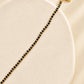 Close-up wrist view of a dainty black onyx bracelet with tiny faceted black beads and subtle gold accents.