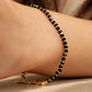 A close-up of a delicate black gemstone bracelet crafted in faceted black onyx and gold vermeil beads, worn on a woman's wrist.