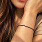 A close-up lifestyle shot of a woman wearing a delicate black onyx beaded bracelet with gold vermeil beads on her wrist.