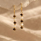 Pair of Tiger's Eye and Mother of Pearl gemstone bar earrings dangling against a warm neutral background.