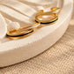 Black and white enamel gold ear cuffs displayed together on a soft neutral jewellery tray.
