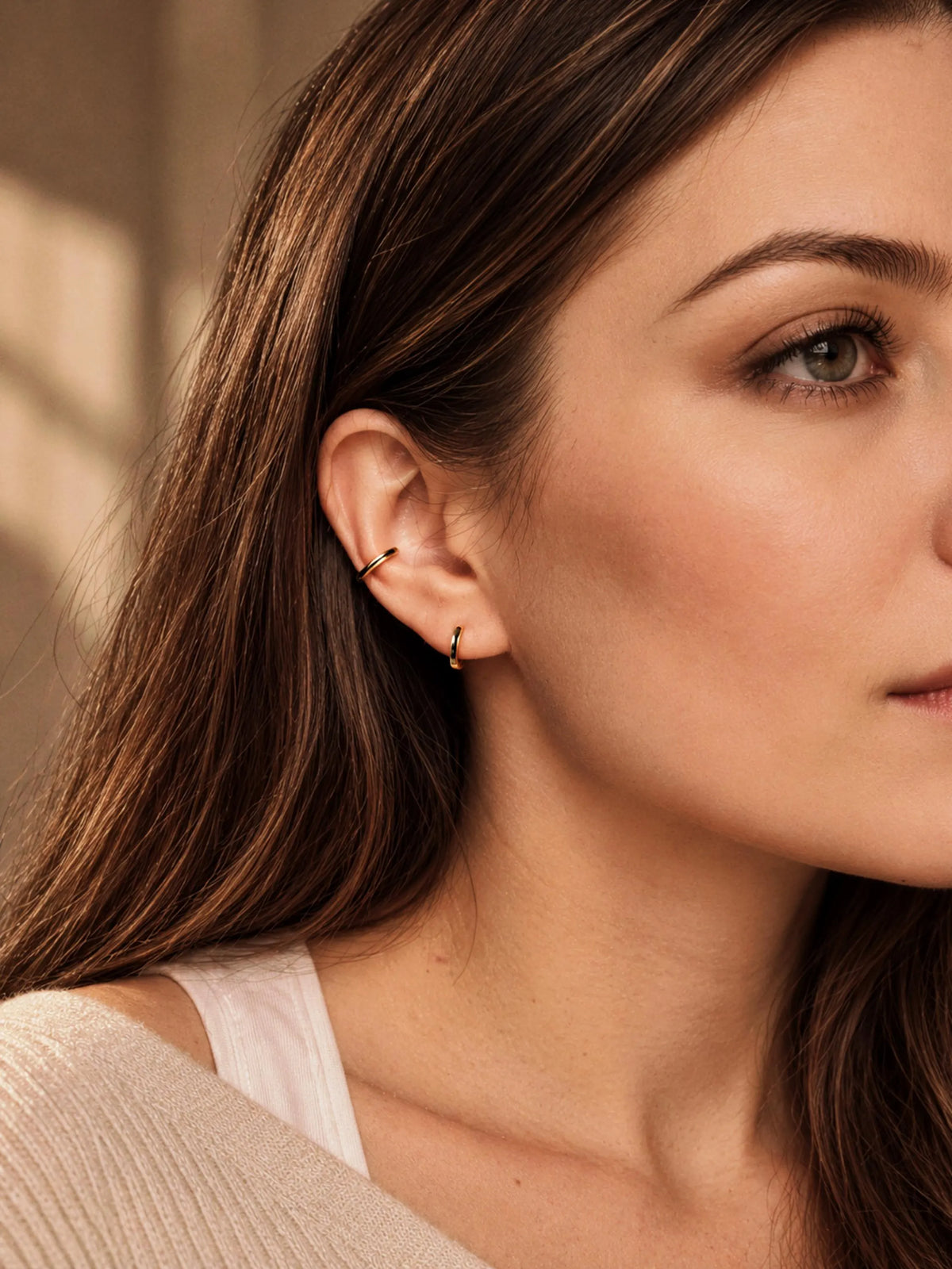 Woman wearing a minimalist gold enamel ear cuff on the cartilage with a clean everyday jewellery look.
