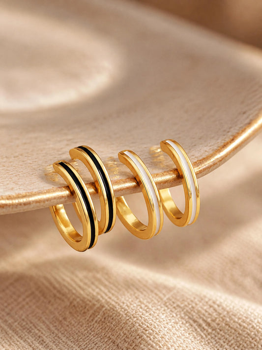 A set of thin enamel gold ear cuff earrings, one pair in black enamel and one pair in white enamel, crafted in 18k gold vermeil.