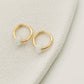 Two exquisite golden white jade huggie hoop earrings elegantly resting on a surface, showcasing their natural beauty.