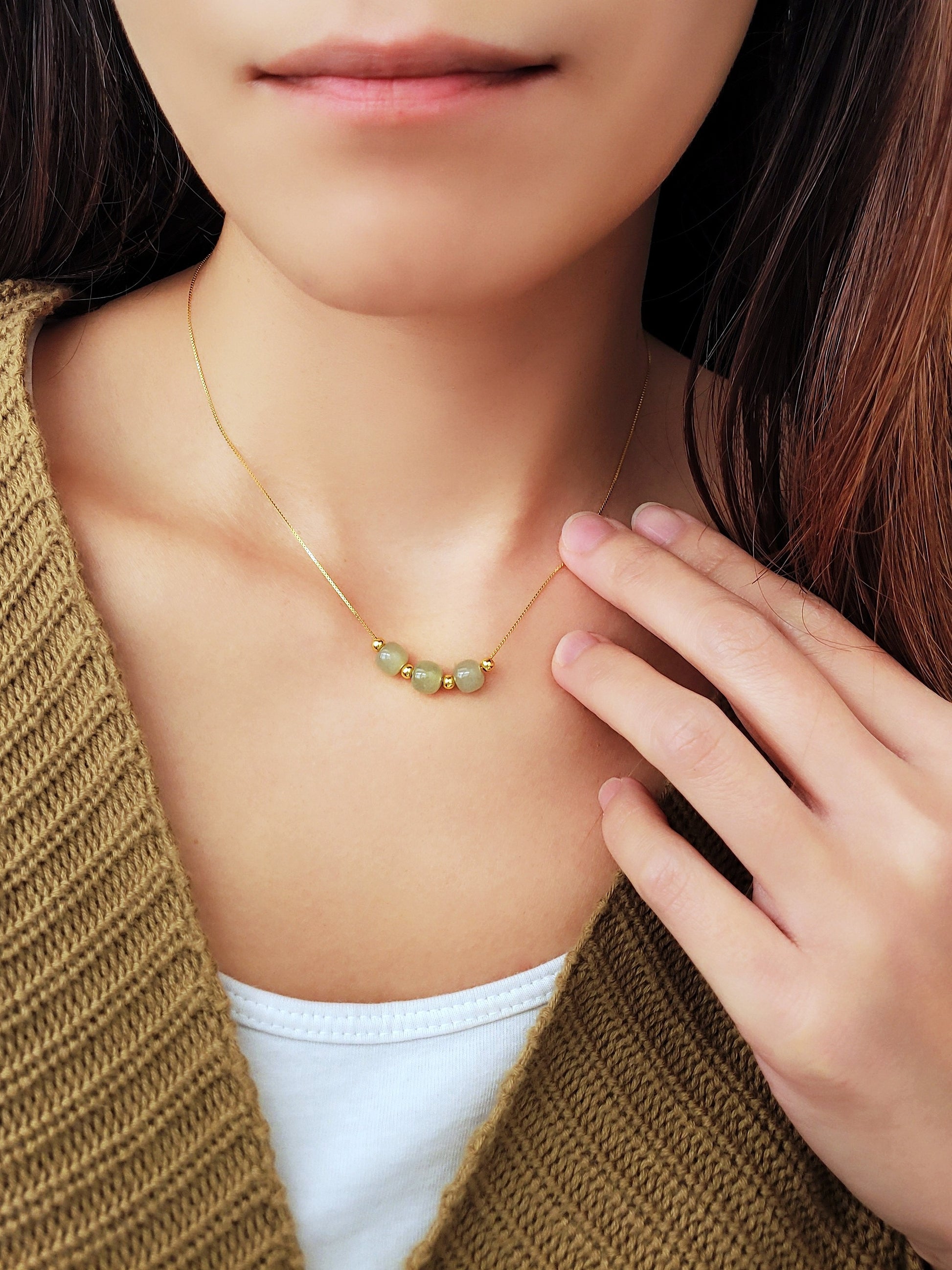 A woman wearing elegant jade pendant necklace with a minimalist design, featuring natural jade gemstones that are believed to bring calming energy, shown on an adjustable chain.