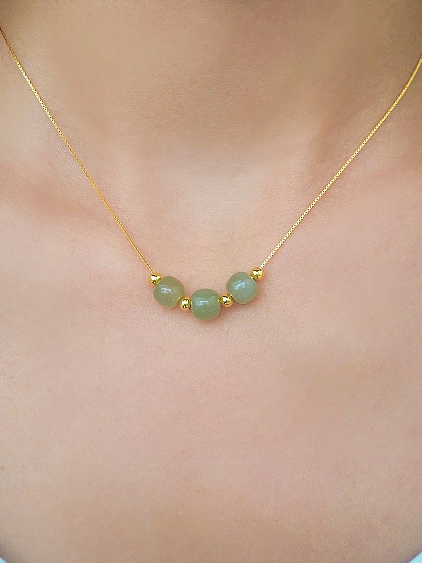 A woman wearing elegant jade pendant necklace with a minimalist design, featuring natural jade gemstones that are believed to bring calming energy, shown on an adjustable chain.