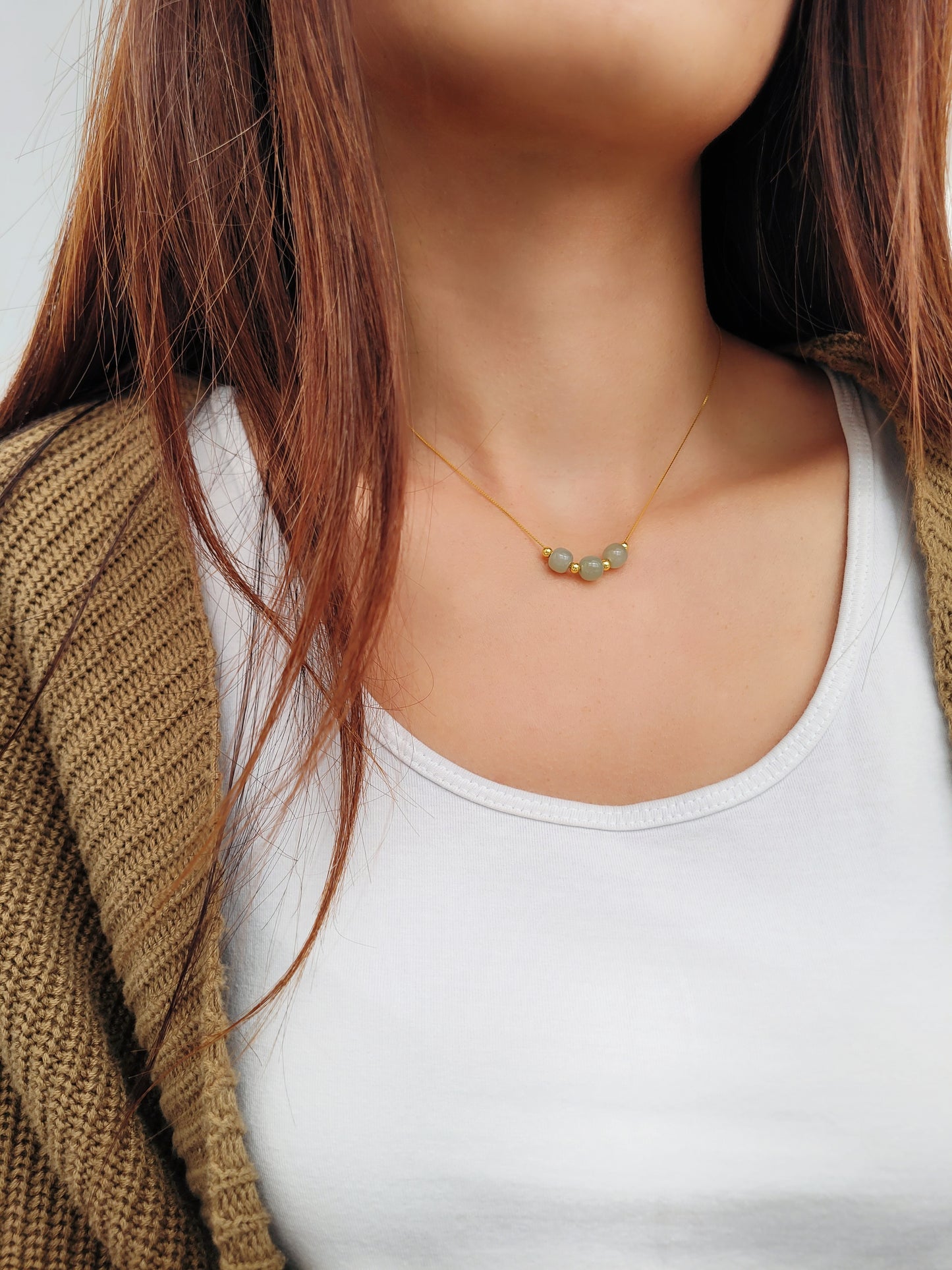 A woman wearing elegant jade pendant necklace with a minimalist design, featuring natural jade gemstones that are believed to bring calming energy, shown on an adjustable chain.