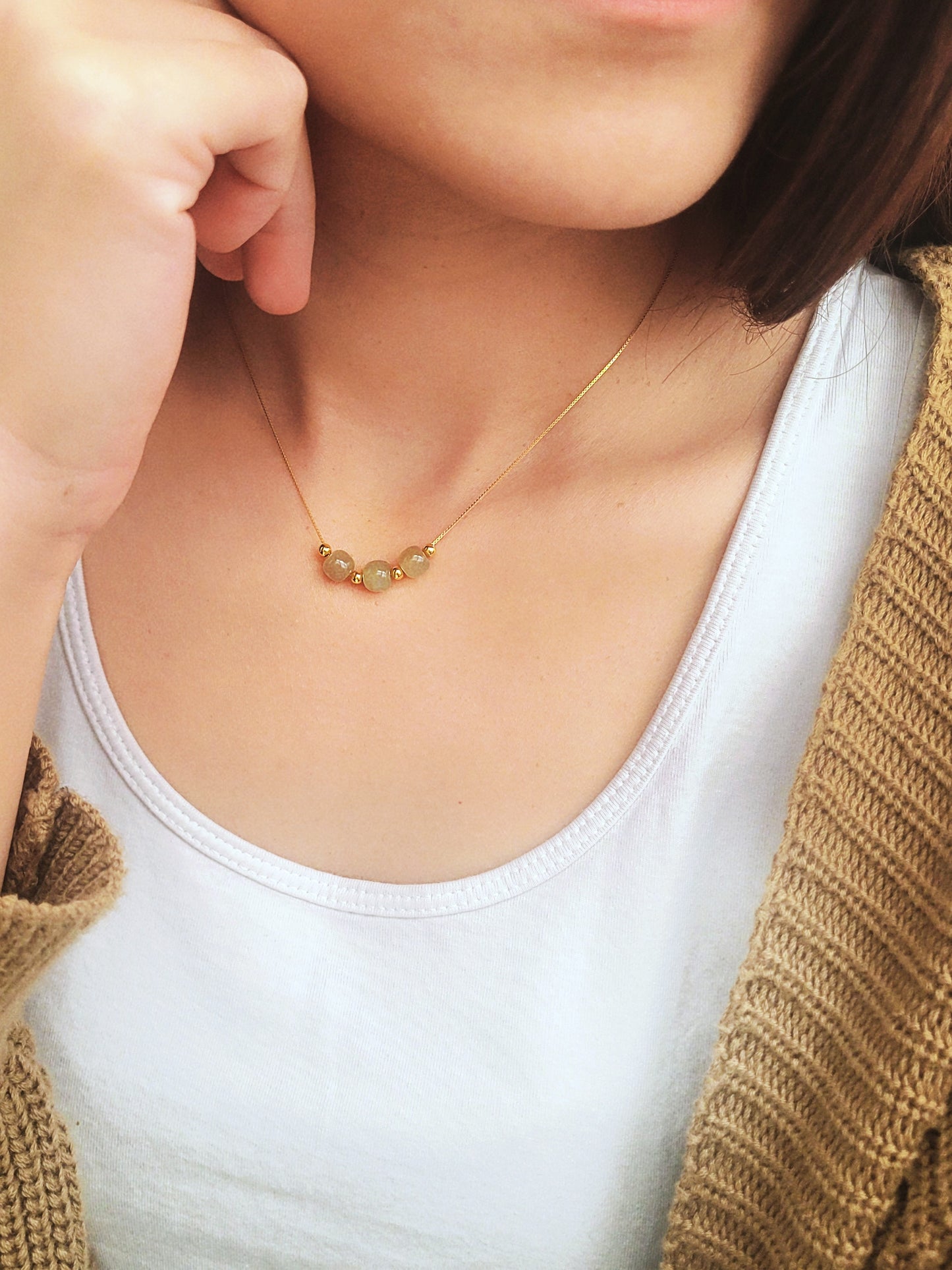 A woman wearing elegant jade pendant necklace with a minimalist design, featuring natural jade gemstones that are believed to bring calming energy, shown on an adjustable chain.