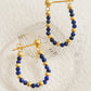 Hoop earrings with blue lapis lazuli gemstone and gold beads on a light background