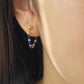 Close-up of an ear wearing a gold and blue gemstone beaded earring.