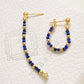Pair of hoop earrings with blue beads and gold accents on a textured white surface.