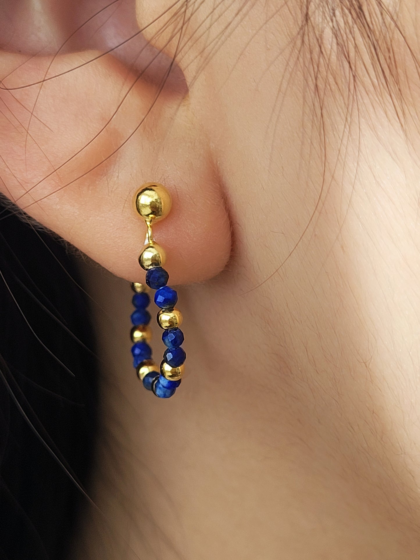 Gold and blue lapis lazuli beaded earring worn on an ear