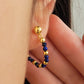 Close-up of a gold and blue beaded earring worn on an ear. Perfect birthday gift for mom
