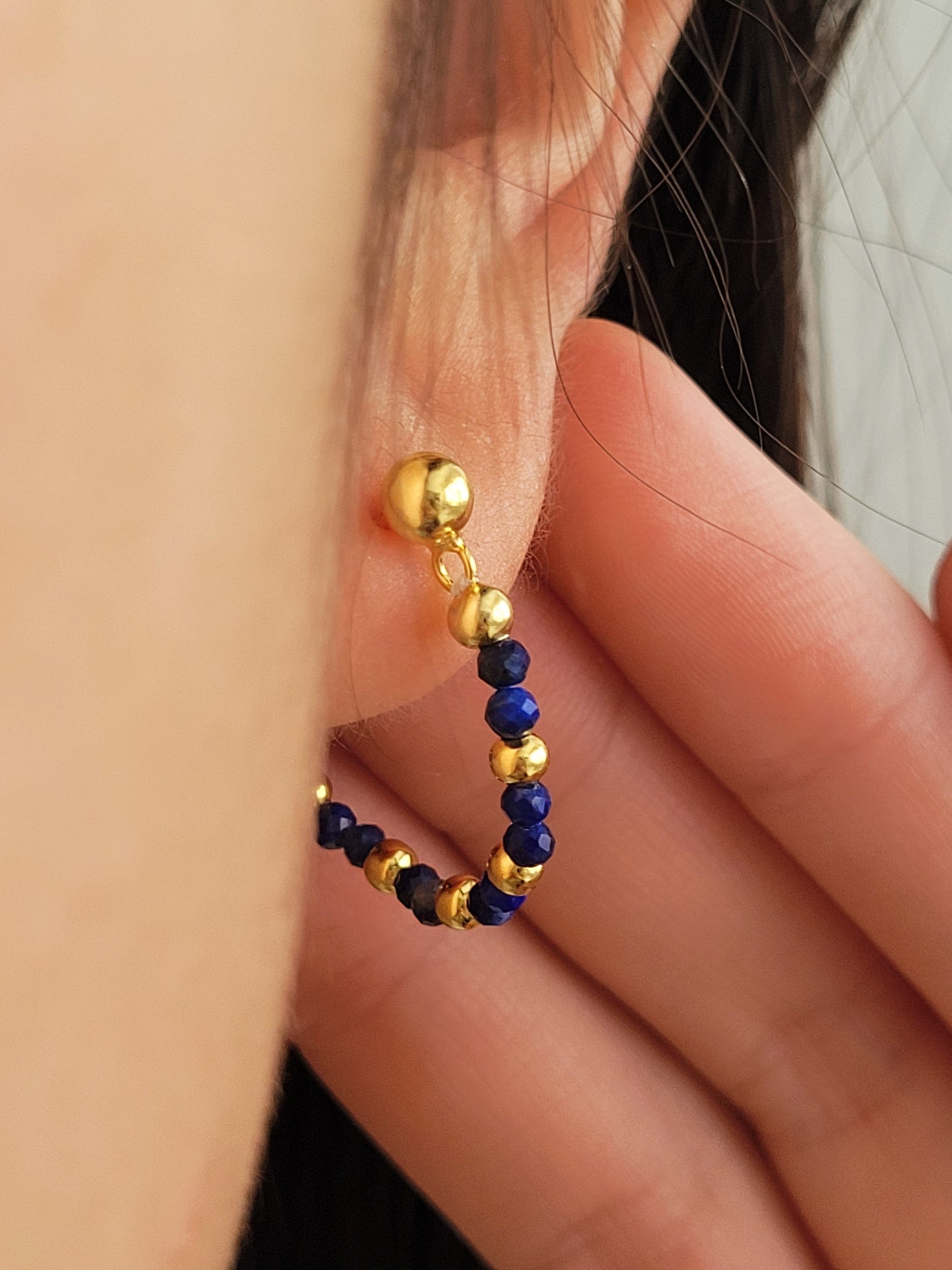 Close-up of a gold and blue beaded earring worn on an ear. Perfect birthday gift for mom
