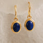 Gold earrings with blue stones on a beige background