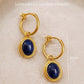 Gold hoop earrings crafted in 22k gold vermeil with lapis lazuli stones on a beige background