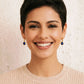 Woman with short black hair wearing minimalist lapis lazuli earrings against a neutral background.