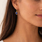 Close-up of a woman wearing a 22k gold earring with a blue lapis lazuli gemstone.
