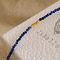 Close up of a deep blue lapis lazuli gemstone and gold bead bracelet featuring faceted natural stone beads and gold-plated accents on JaBelle Jewellery box.