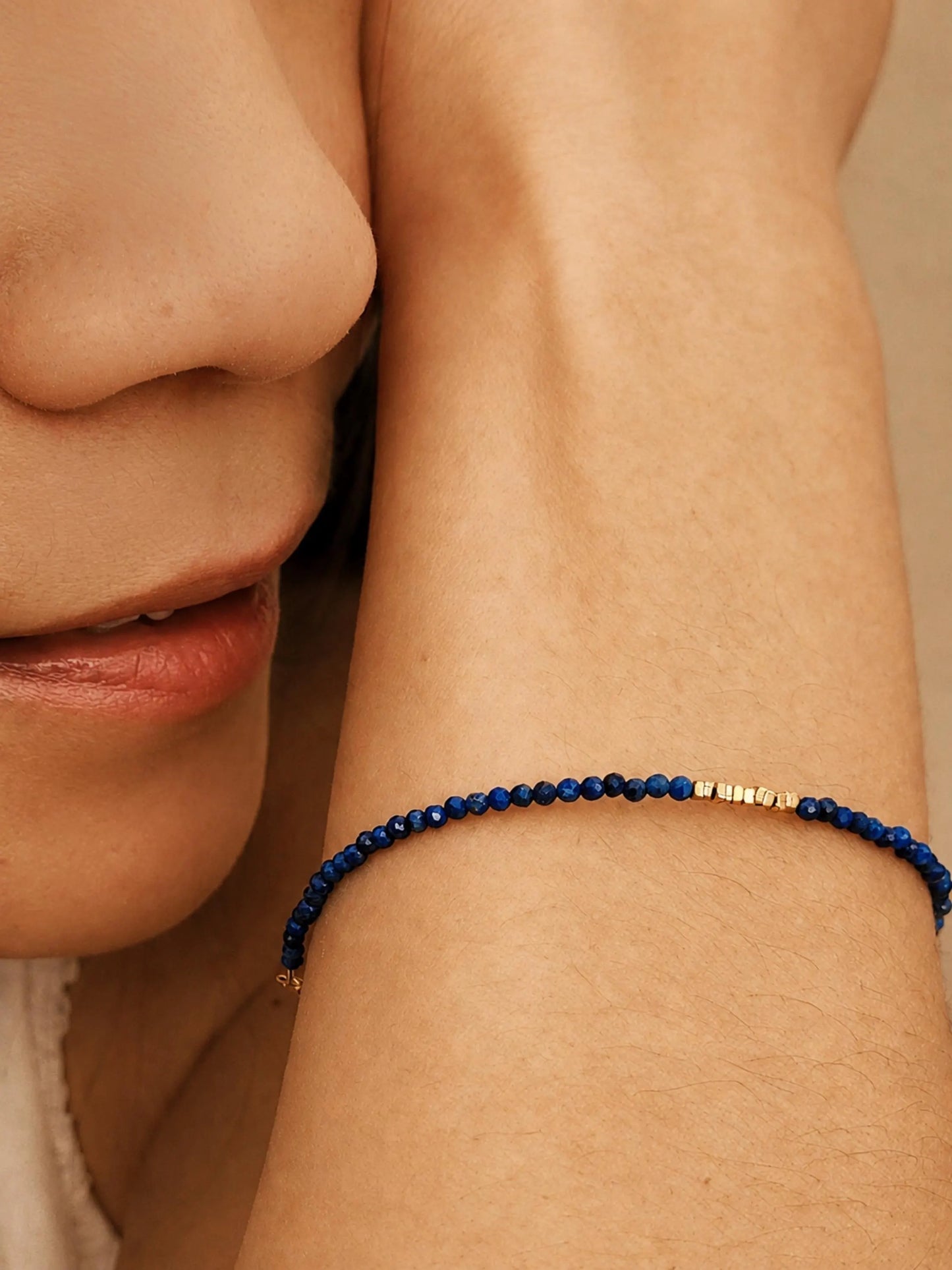 A dainty thin lapis lazuli beaded bracelet featuring tiny faceted blue bead gemstone interspersed with gold accents, perfect jewellery gift for September birthday girls