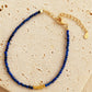A beaded 18k gold vermeil bracelet featuring faceted lapis lazuli gemstone in deep blue color displayed on an aesthetic beige color stone, delicate and minimal style for everyday wear.