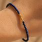 A delicate, handmade lapis lazuli bracelet, worn on woman wrist, featuring small faceted deep blue gemstone beads and gold vermeil accents, dainty minimalist jewellery