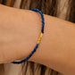 Model wearing a minimalist lapis lazuli beaded bracelet featuring tiny blue faceted gemstones and small gold accent beads.
