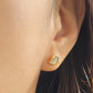 Close up of a woman wearing a gold stud earrings featuring natural leaf shape paved with cubic zirconia stone. 