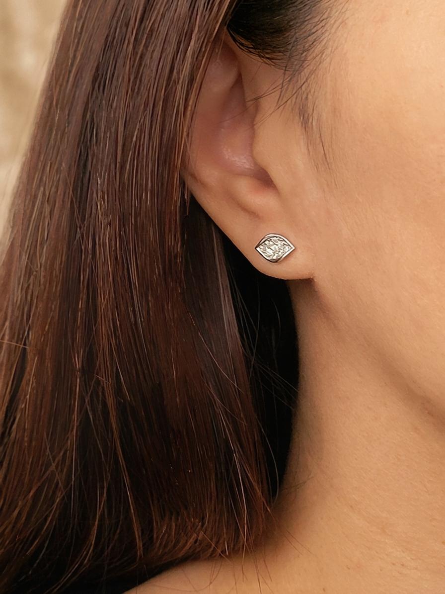 Close up of a woman wearing a silver stud earrings featuring natural leaf shape paved with cubic zirconia stone. 
