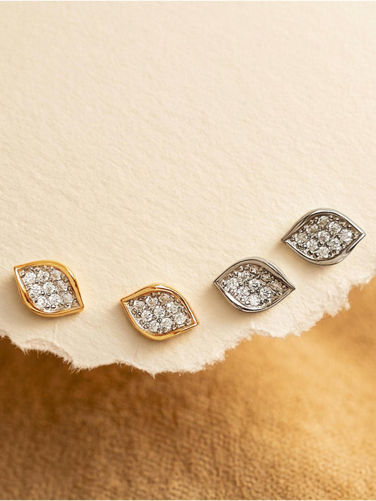 A collection of four sculptural leaf cluster earrings displayed card paper, showing the design in both 18k gold vermeil and 925 sterling silver with pave cubic zirconia details.