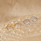 A collection of four sculptural leaf cluster earrings displayed on a glass surface, showing the design in both 18k gold vermeil and 925 sterling silver with pave cubic zirconia details.