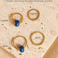 Set of mini blue enamel bead huggie hoop earrings on an aesthetic beige stone surface with dimensions